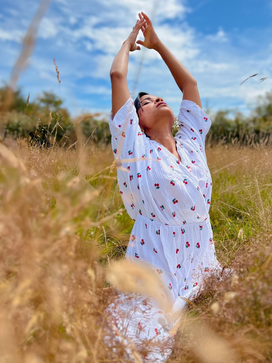 Oshikha in an open field, arms raised in prayer